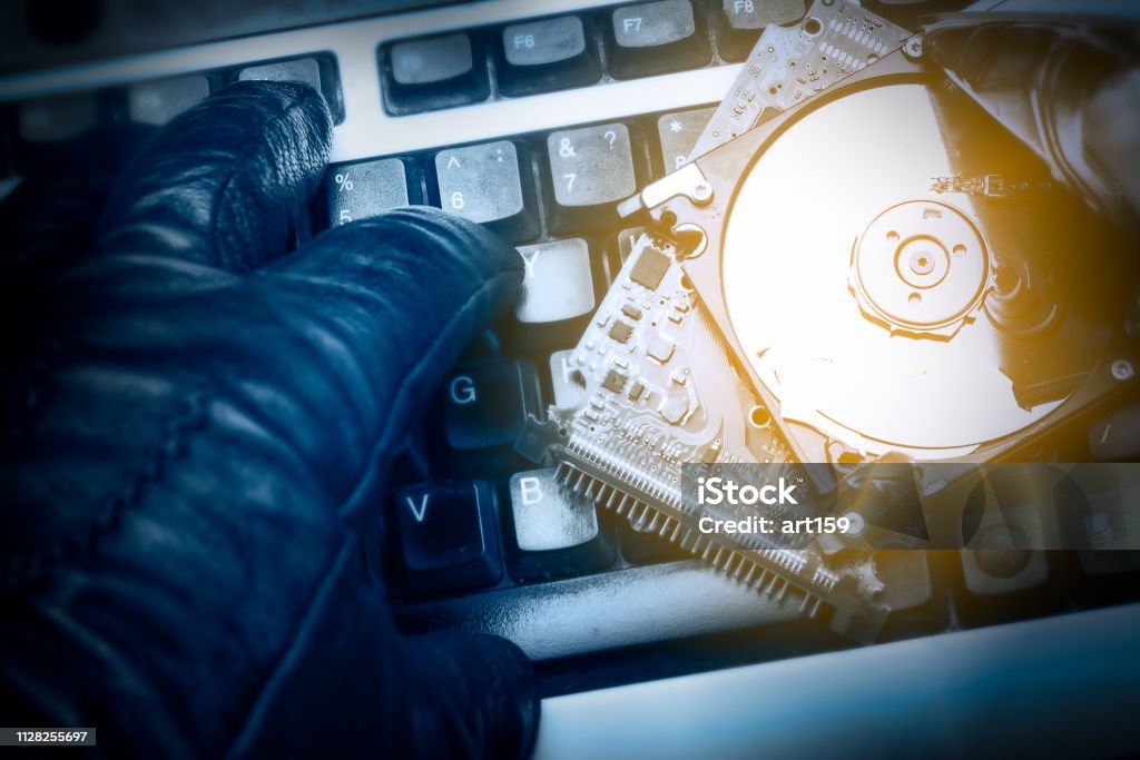 Cybercriminal's hand on a keyboard. Hacked computer hard drive. Cybercrime concept Blue Stock Photo