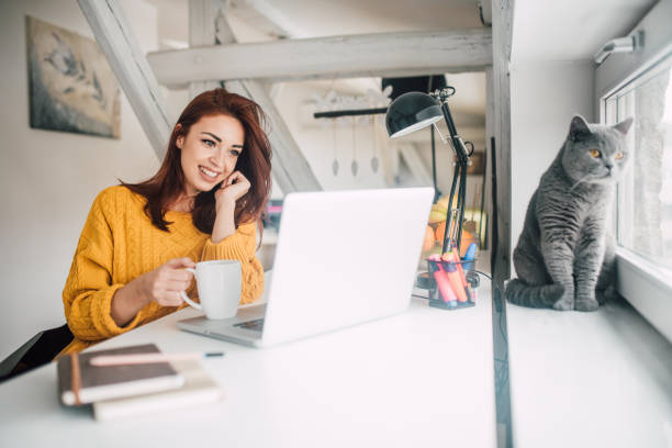 istock Smiling pretty young redhead working on a laptop 1128256822