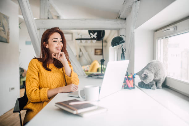 istock Smiling young redhead working on a laptop 1128256828