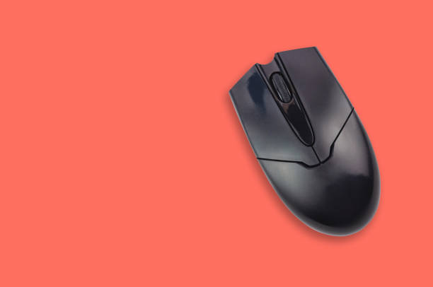 istock Single black plastic optical computer mouse on office table living coral color. Top view. Copy space for your text. Business or education concept 1128259236