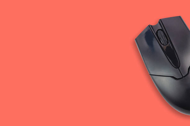 istock Single black plastic optical computer mouse on office table living coral color. Top view. Copy space for your text. Business or education concept 1128259242