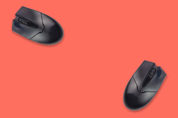 istock Two black plastic optical computer mouses on office table living coral color. Top view. Copy space for your text. Business or education concept 1128259249