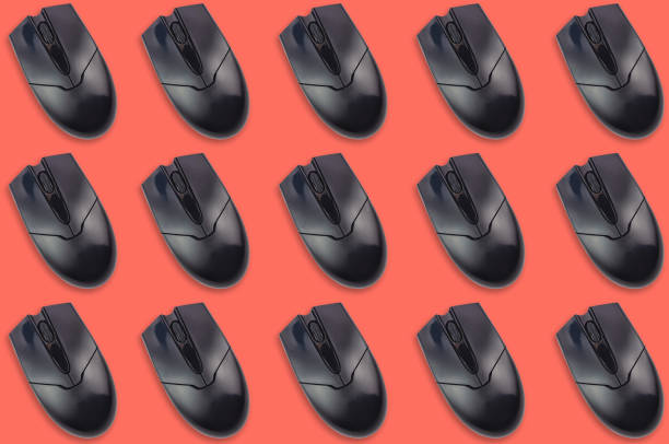 istock Rows of black plastic optical computer mouses on office table living coral color. Top view. Seamless pattern 1128259254