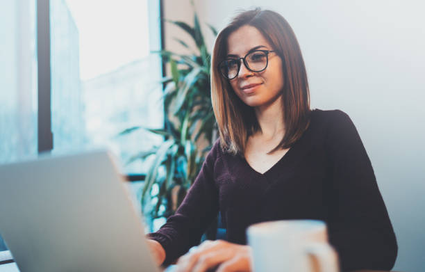 istock Young smiling girl using mobile laptop for looking a new business solution during work process at night office.Blurred background. 1128265932