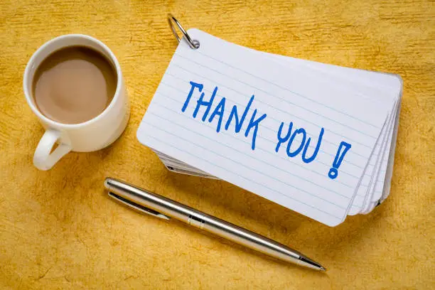 thank you - handwriting on a stack of index cards with a cup of coffee and  a pen