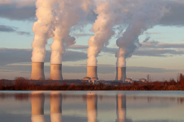 Light from a sunset over the power plant. 12 december 2018, Basse Yutz, Yutz, Moselle, Lorraine, France. The Cattenom nuclear power station with cooling towers and vapor clouds lit by the setting sun. reflet stock pictures, royalty-free photos & images