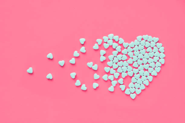 white heart shaped candies on a pink paper background. broken heart or pearts gethering love concept. - coral break imagens e fotografias de stock