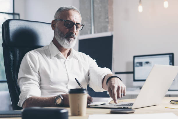 istock Pensive businessman working at modern coworking office. Confident man using contemporary mobile laptop. 1128279104