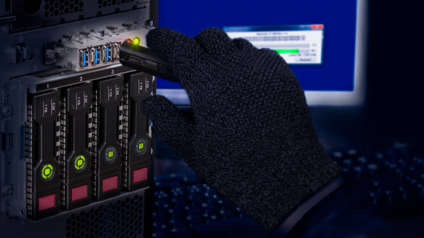 Hand in black glove holding USB flash drive. Computer data theft detail Spy or saboteur is copying secret information from a server with dark hot-swap hard disks. Storage device. Concept of cyber crime or espionage sabotage stock pictures, royalty-free photos & images