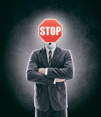 Stop sign as head on businessman in a suit with arms crossed - Image manipulation