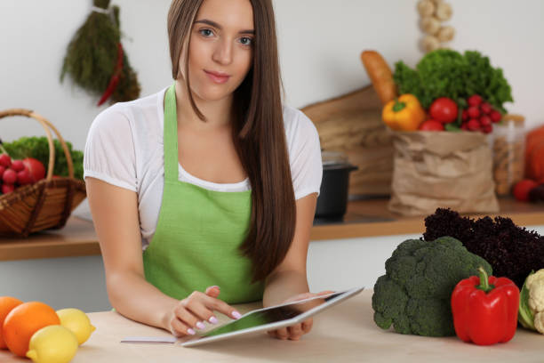 istock Young woman using tablet computer while cooking in kitchen. Householding, tasty food and digital technology in lifestyle concepts 1128280318