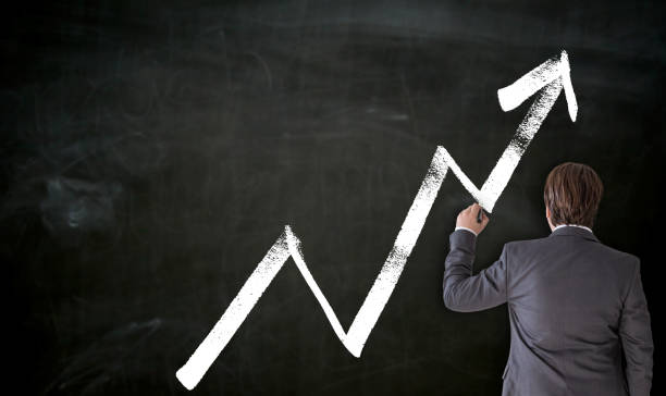 istock Businessman paints with chalk graph on blackboard 1128281049