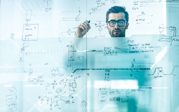 istock Young engineer making a business plan and drawing diagram on a glass wall. 1128289510