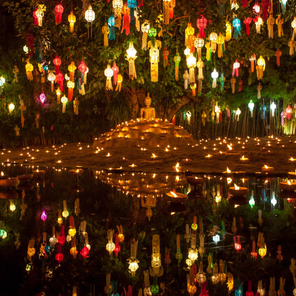 istock Buddha image surrounded by candles and colourful lanterns. 1128295667