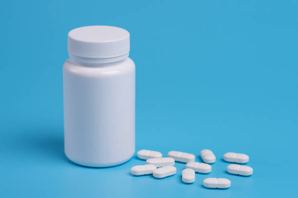 istock White pills, tablets and white bottle on blue background. Copy space for text 1128298374