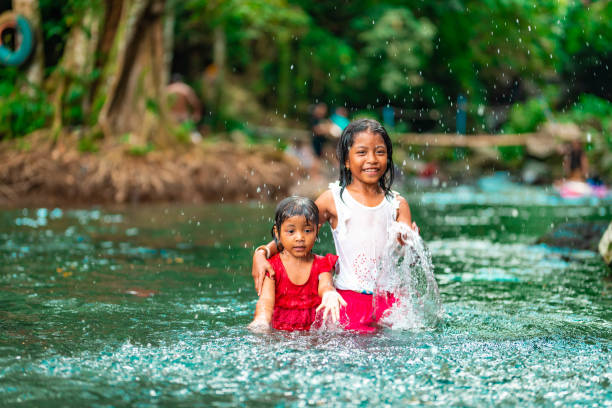 istock Two little indonesian girls having fun in a river 1128299999