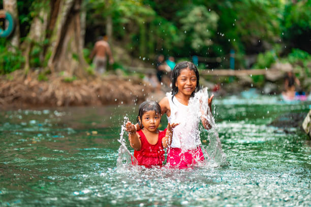Two little indonesian girls having fun in a green river.
