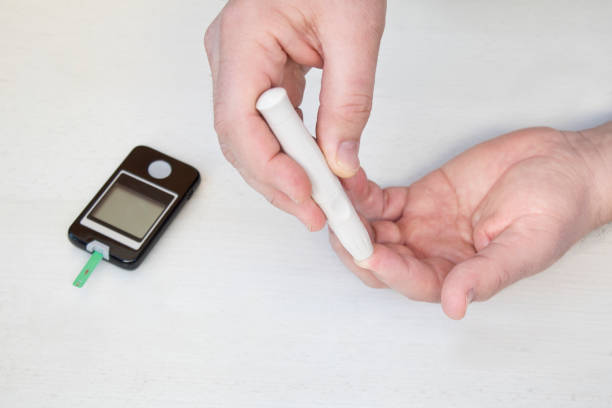 mano delle persone controlla il diabete e il monitor della glicemia alta con manometro digitale. concetto di assistenza sanitaria e medica - blood sugar test examining instrument of measurement diabetes foto e immagini stock