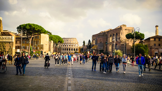 Tourists walk along Via dei Fori Imperiali at the Roman Forum with the Colosseum in background