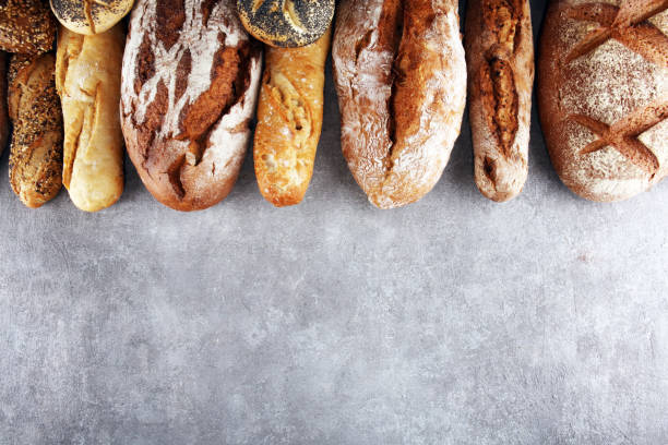 istock Assortment of baked bread and bread rolls on stone table background 1128306505