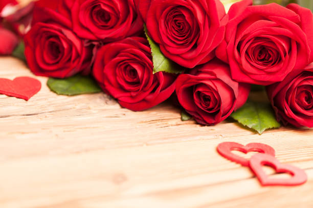 istock Red roses with hearts on wooden table 1128308582