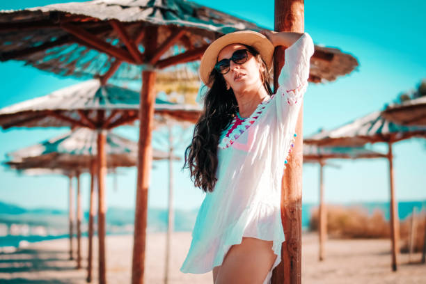 istock Smiling Young Woman Under Beach Parasol 1128309011