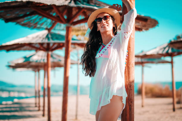 istock Smiling Young Woman Under Beach Parasol 1128309048