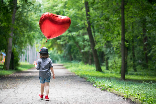 niño con globo de forma de corazón - child balloon outdoors little boys fotografías e imágenes de stock