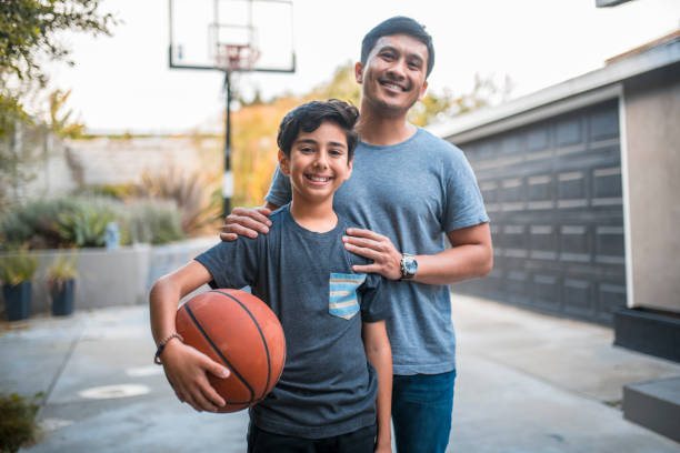 happy boy and father standing at basketball court - multi ethnic group family child standing imagens e fotografias de stock