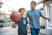 istock Boy spinning basketball while walking by father 1128316823