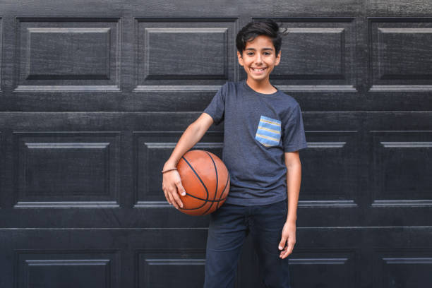 Boy holding basketball against wall
