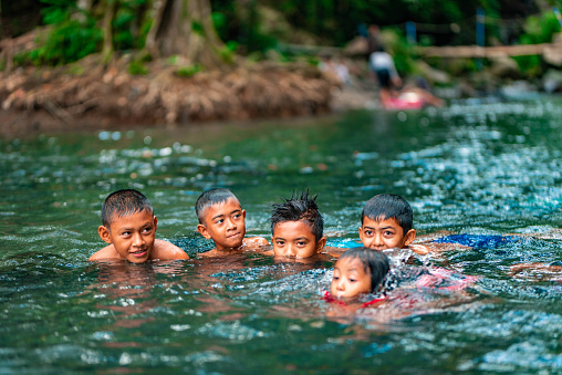 Indonesian children playing and having fun in a river.