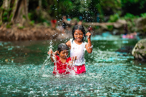 Two little indonesian girls having fun in a green river.