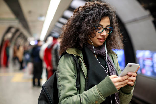 istock Young woman using mobile phone in the subway station 1128326410