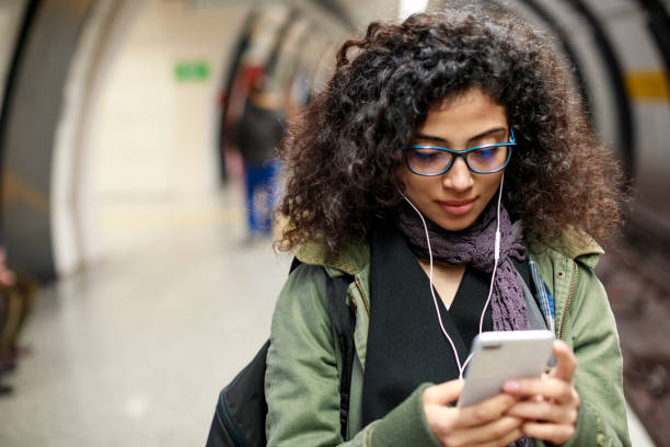 istock Young woman using mobile phone in the subway station 1128326955