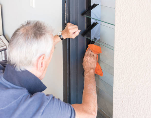 istock Older man cleaning louvre windows with orange cloth 1128326960