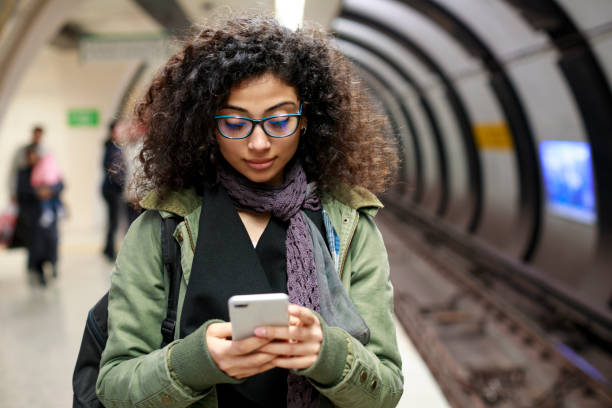 Young female commuter using mobile phone in the subway station Young female commuter using mobile phone in the subway station subway platform stock pictures, royalty-free photos & images