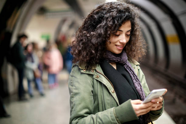 istock Young woman using mobile phone in the subway station 1128327081