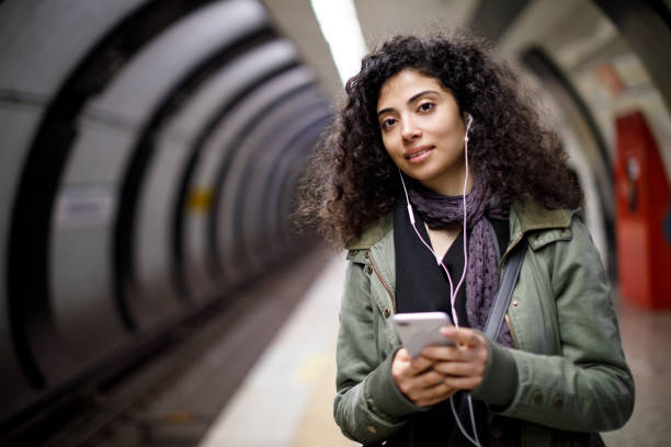 istock Young female commuter using mobile phone in the subway station 1128327119
