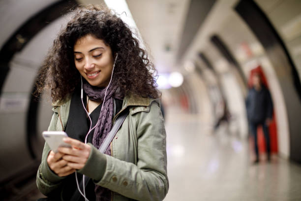 istock Young female commuter using mobile phone in the subway station 1128327151