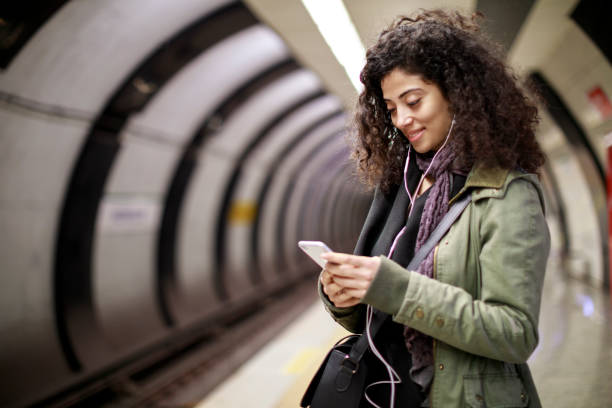 istock Young female commuter using mobile phone in the subway station 1128327195