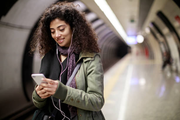 istock Young female commuter using mobile phone in the subway station 1128327199