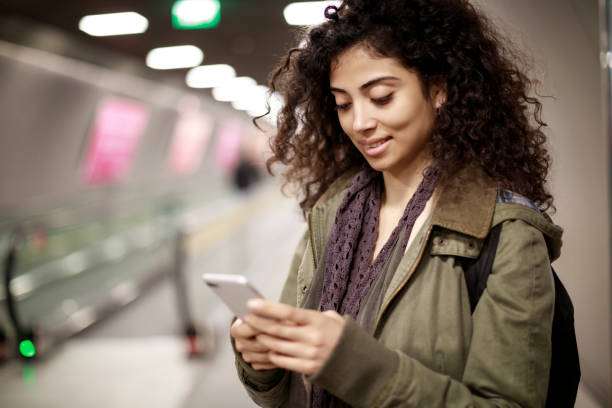 istock Young woman using mobile phone in the subway station 1128327228