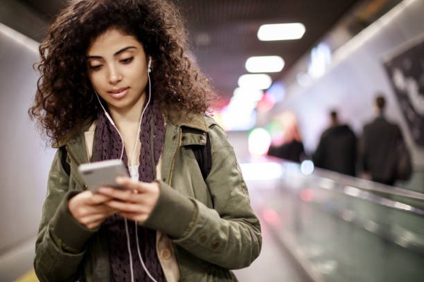 istock Young woman using mobile at subway station 1128327241
