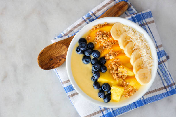 istock Pineapple, mango smoothie bowl with coconut, bananas, blueberries and granola, top view on marble 1128328068