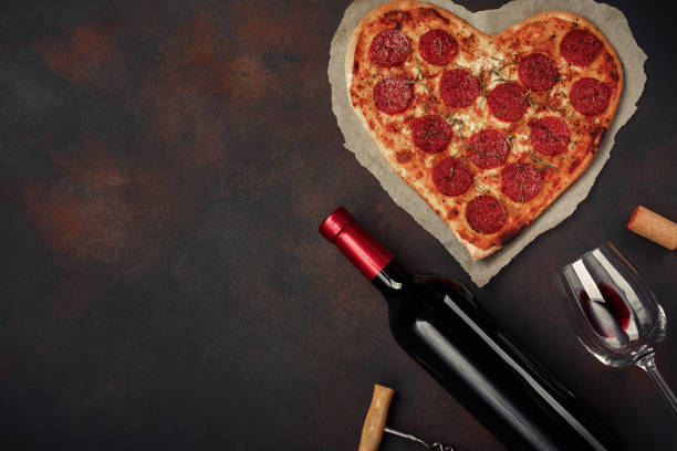 heart shaped pizza with mozzarella, sausagered with a bottle of wine and wineglas on rusty background. - cork tops imagens e fotografias de stock