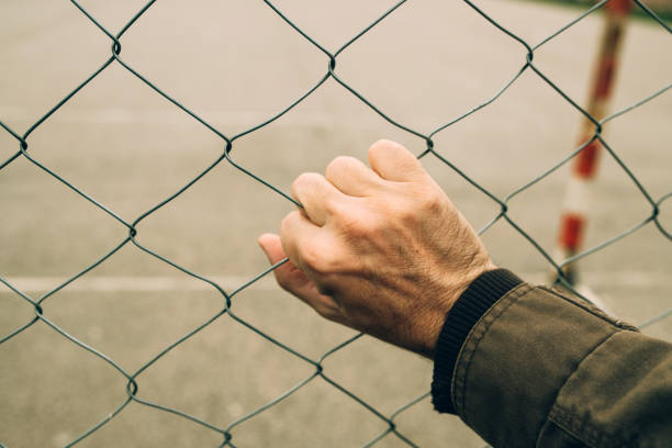 Male hand on chainlink fence, illegal immigration concept