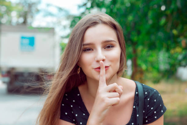 donna che chiede silenzio o segretezza con le dita sulle labbra silenzio mano gesto parco cittadino - patronize foto e immagini stock