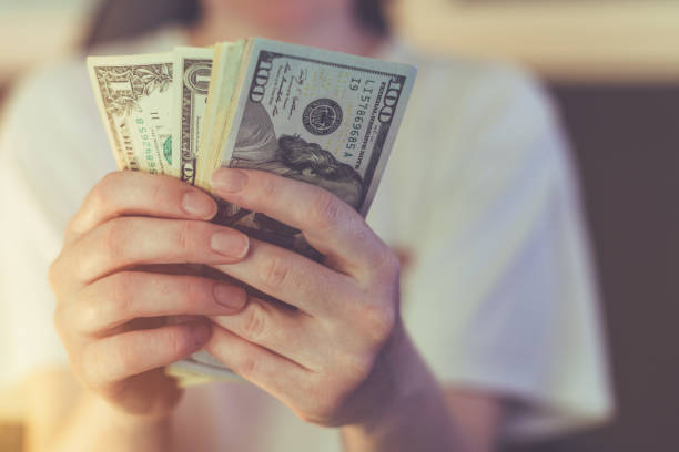 istock Casual woman is counting american dollar banknotes 1128335929