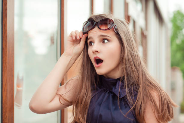 istock Surprised young woman holding sunglasses up 1128335965